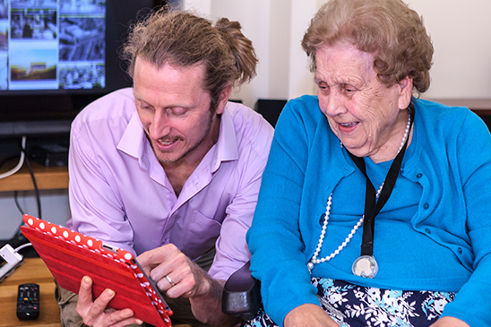 facilitator with older lady on an ipad